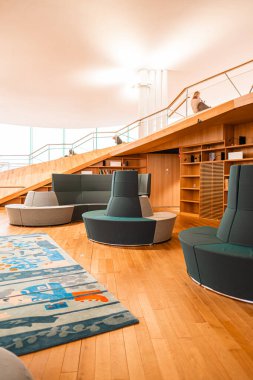 Modern kütüphanenin içinde şık mobilyalar ve ahşap elementler sergileniyor. Açık tasarım ve oturma alanları huzurlu bir ortamda okumak, çalışmak ve dinlenmek için davetkar bir ortam yaratıyor.