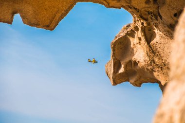 Canlı bir deniz uçağı, eşsiz kıyı kaya oluşumları tarafından mükemmel çerçevelenmiş engin gökyüzünde pürüzsüz bir şekilde süzülür. Sahne, doğa ve havacılık macerasının uyumlu bir karışımını yakalar..