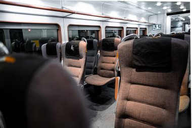 Modern bir trenin içi boş, minderli rahat koltuklar, huzurlu bir yolculuk için mükemmel. Oturma yerleri, gezginler için rahatlatıcı bir atmosfer yaratacak bireysel okuma ışıklarını içerir..