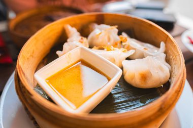 Buharda pişirilmiş hamur köfteleri geleneksel bambu sepetinde lezzetli bir sos ile servis edilir, lezzetli ve iştah açıcı bir düzende otantik Asya gastronomisi sergilenir..