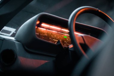 Parlak göstergeleri ve direksiyonu olan klasik bir arabanın yakın görüntüsü. Atmosferik ışıklandırma altında retro otomotiv tasarımının özünü yakalar.