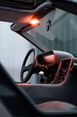 Aydınlatılmış kontrolleri ve gösterişli bir gösterge paneli olan modern bir arabanın gelecekteki tasarımını keşfedin. Gelişmiş otomotiv teknolojisini şık düşük ışık ortamında sergiliyor..