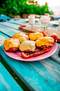 Lezzetli ızgara çizburgerler, açık hava manzarasında canlı bir masada kızarmış kırmızı biberle servis edilir. Yaz zamanı arkadaşlarınız ve ailenizle toplanmak ya da piknik yapmak için mükemmeldir..