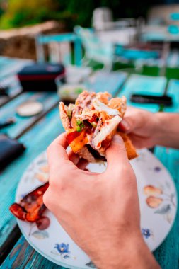 Açık hava yemeği sırasında elde tutulan lezzetli sandviç taze malzemelerin altını çizmek ve canlı bir fresk yemek düzeneği. Gelişigüzel yemek ve leziz yemek tasvirleri için mükemmel..