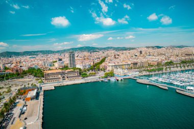 Bir sahil şehrinin panoramik manzarası, canlı rıhtım yapıları, rıhtım tekneleri, ve güneşli mavi gökyüzünün altında yayılan bir kentsel alan.