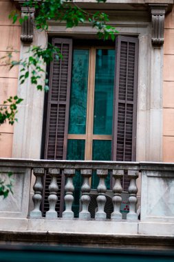 Şehir mimarisinde klasik bir balkon, kaya balyaları, ahşap panjurlarla süslenmiş bir pencere ve atmosferik yeşillik var. Şehir manzaralarında zamansız bir Avrupa tasarımı örneği.