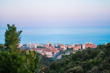 Bereketli bitki örtüsüyle çevrili kıyı kentsel alanı, parıldayan okyanus suları, ve sakin bir gökyüzü doğal ve kentsel uyum açısından zengin resimsel bir manzara yaratıyor..