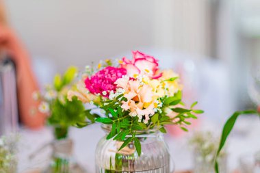 Parlak pembe, krema ve yeşil renkte narin bir vazoda bulunan canlı bir çiçek aranjmanı. Kutlamalar için ideal bir renk..