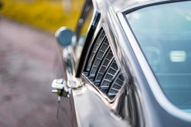 Penceresinin detayları, krom aksanları ve klasik nostalji ve otomotiv tarihinin zamansız zarafetini anımsatan klasik bir arabanın yakın plan görüntüsü..