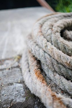 Doğal dokuları olan sarmalanmış bir ipe odaklan. Ayar tarafsız tonları vurguluyor ve halatın sert görünüşü, kırsal veya endüstriyel estetiği vurgulamak için ideal..