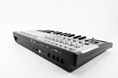 A sleek MIDI keyboard controller featuring black and white keys, multiple customizable knobs, and connection ports, perfect for music production and studio work in a professional or home setting. clipart