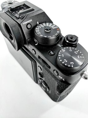 Close-up image of a black digital camera showcasing its dials, buttons, and design details under bright light on a white surface. Perfect for showcasing camera technology and photography equipment. clipart