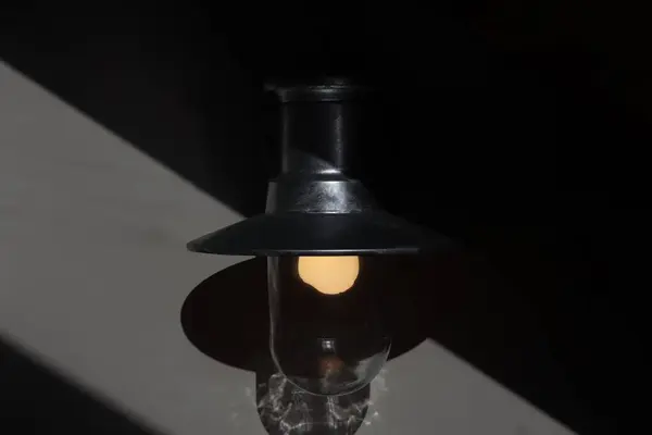 Koyu bir uzayda eski bir lambanın yakın plan çekimi. Metal bir fenerin yumuşak, ılık bir parıltısının yüksek kaliteli fotoğrafı..