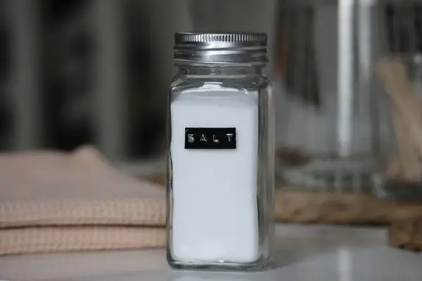 Modern bir mutfakta tuzla dolu basit bir cam kavanoz. Ev yemeği ve baharat gerekli. Yüksek kaliteli stok fotoğrafı.