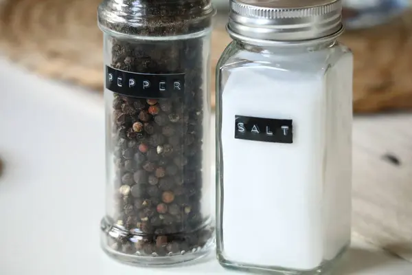 Biber öğütücüsünün yanında beyaz tuz dolu cam tuz karıştırıcının yakın plan görüntüsü. Yüksek kaliteli stok fotoğrafı.