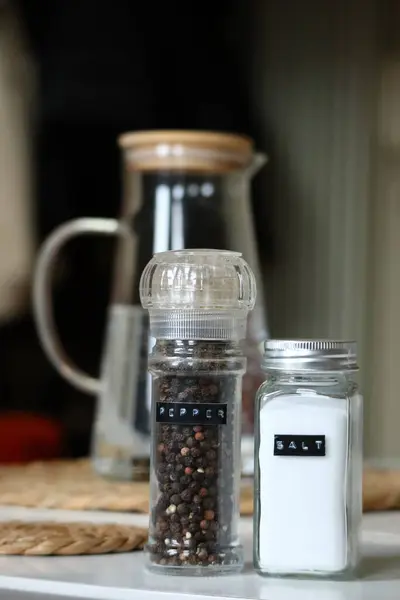 Arka planda bulanık bir su testisi ile tamamlanmış tuzluk ve biberlikleri gösteren minimalist bir yaşam. Yüksek kalite fotoğraf