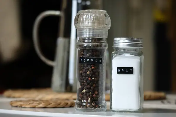 Arka planda bulanık bir su testisi ile tamamlanmış tuzluk ve biberlikleri gösteren minimalist bir yaşam. Yüksek kalite fotoğraf