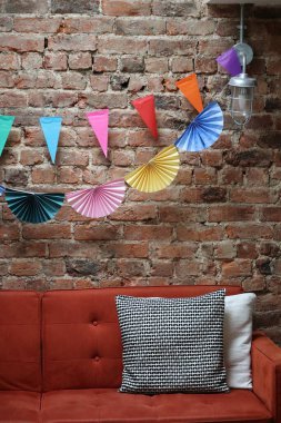 A cosy interior with garland decorations hanging on an exposed brick wall. Festive house decorations, stock photo. clipart