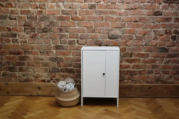 Bu iç mekan kırmızı tuğladan bir duvar, minimalist beyaz bir dolap ve yuvarlanmış atımlarla dolu bir sepet içeriyor, rahat ve çağdaş bir atmosfer yaratıyor..