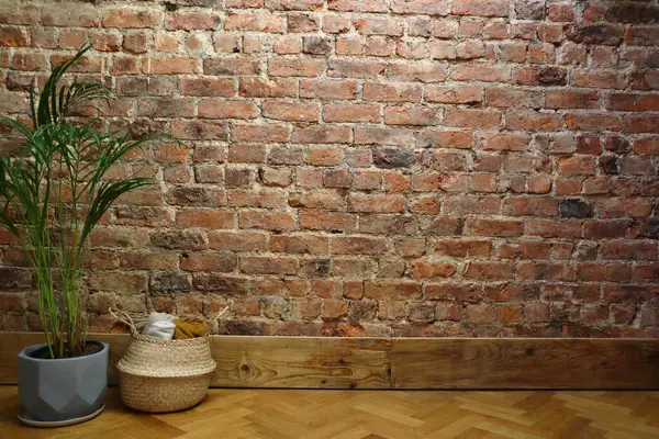 Samimi bir iç köşe, desenli kırmızı tuğla bir duvar, saksı bitkisi ve katlanmış atımlarla dolu bir sepet. Bu resim arkaplan, iç tasarım ilhamı ve dekor temaları için uygundur