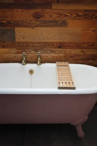 Kırsal ahşap bir duvara karşı klasik bir pembe pençe küveti. Yüksek Kalite Stok Fotoğrafı