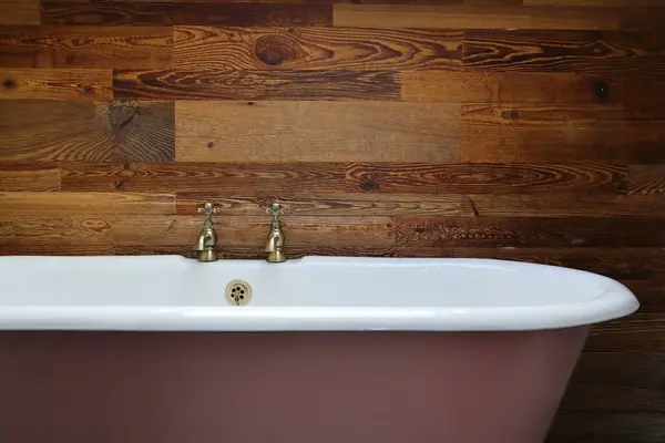 Bu yakın çekim görüntüsü, ahşap bir duvara karşı pirinçle döşenmiş antika bir küvet sunuyor. Tasarım projeleri, ev dekorasyonu ilhamı veya arkaplan olarak ideal.