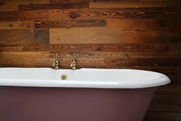 Bu yakın çekim görüntüsü, ahşap bir duvara karşı pirinçle döşenmiş antika bir küvet sunuyor. Tasarım projeleri, ev dekorasyonu ilhamı veya arkaplan olarak ideal.