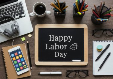 İşçi Bayramı için ahşap bir çalışma alanı düzenlemesinin üst görüntüsü. Laptop, akıllı telefon ve yazılı karatahta da dahil. Çeşitli kırtasiye elemanları modern çalışma ortamını geliştirir.