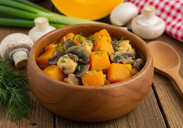 Taze dereotuyla süslenmiş sağlıklı ve canlı bir kâse balkabağı, mantar ve karnabahar yahnisi. Bu kırsal ve lezzetli yemek sonbaharın özünü temsil ediyor, besleyici ve sağlıklı bir mutfak deneyimi sunuyor. S 'nin mükemmel bir karışımı
