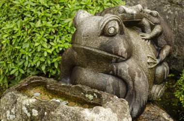 İçinde bozuk paralar ve kurbağalar bulunan bir çeşme.