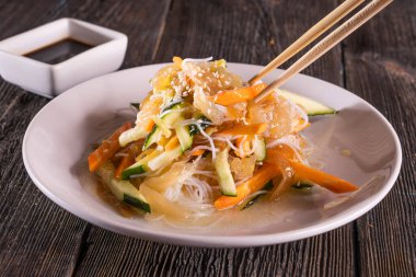 Ahşap masada Asya usulü doğranmış salata. Çin yemeği. Tahta çubuklar, soya sosu..