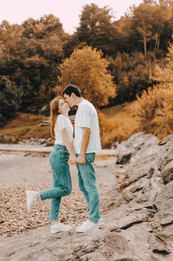 Genç bir çiftin portresi. Karı koca, güz parkında birbirlerine bakarak gülümsediler. Sonbahar parkında birbirine aşık genç bir çiftin açık havada çekilmiş fotoğrafı. Plaj