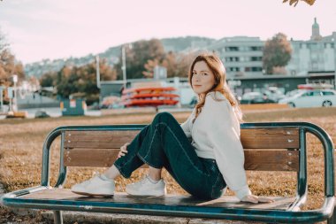 Kot pantolon giymiş duygusal bir kadın model ve sıcak bir Eylül sabahı parkta beyaz ayakkabılar. Çekici beyaz kadın.