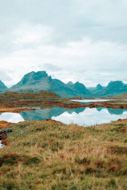 Suya bir dağ yansıtılır ve arka planda bir dağ vardır. Norveç, Lofoten adaları