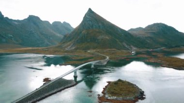Fredvang Köprüsü 'nün havadan görünüşü, araba, Lofoten Adaları, Norveç' teki deniz. Güzel yollu manzara, su, karda kayalar, pembe bulutlu gökyüzü. İHA 'dan üst görünüm