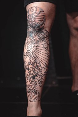 Man with cool tattoos on black background, closeup. Leg clipart