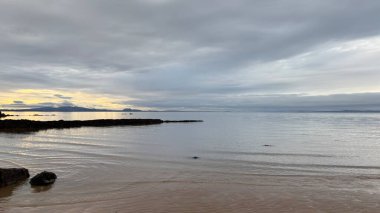 İskoç güzel plajı ve okyanus manzarası. Seton Sands Plajı, Craigielaw. Gün batımı günü. Sakin deniz ve deniz kuşları. Kum, taşlar ve kayalar