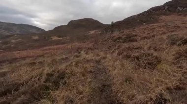 İskoçya İskoçya 'da tepe yürüyüşü. Aberfeldy, Perthshire yakınlarındaki Dun Coillich tepesinde. Schihallian adı verilen ünlü Munro dağının yakınında sık sık uzaklarda belirir. Sonbahar renkleri ve kahverengi fundalık arazide büyüyor..
