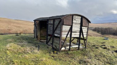 İskoç dağlarında kışın karla kaplı terk edilmiş eski, yıkık dökük tren vagonu. İskoçya 'da açık havada yuvarlanan tepeler. Güzel kırsal kesimde vahşi doğa manzarası