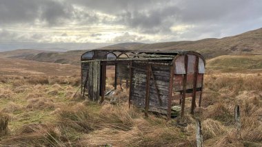 İskoç dağlarında kışın karla kaplı terk edilmiş eski, yıkık dökük tren vagonu. İskoçya 'da açık havada yuvarlanan tepeler. Güzel kırsal kesimde vahşi doğa manzarası
