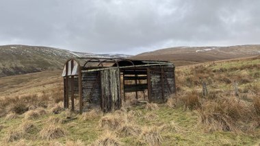 İskoç dağlarında kışın karla kaplı terk edilmiş eski, yıkık dökük tren vagonu. İskoçya 'da açık havada yuvarlanan tepeler. Güzel kırsal kesimde vahşi doğa manzarası