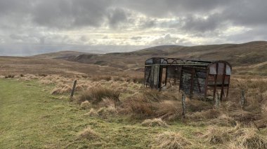 İskoç dağlarında kışın karla kaplı terk edilmiş eski, yıkık dökük tren vagonu. İskoçya 'da açık havada yuvarlanan tepeler. Güzel kırsal kesimde vahşi doğa manzarası