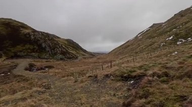 İskoçya 'nın Crieff yakınlarındaki Coire Mhurcha vadisinde yürüyüş. Doğada tepe yürüyüşü, ilkbaharda açık hava, kar ve fundalık. Yuvarlanan dağlar