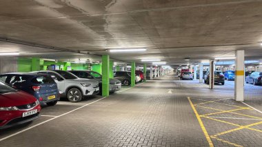 Karanlık yeraltı otoparkı. Şehirli grunge modern yaşam. Huysuz beton bina. Park etmiş arabalar. Sütunlar. Yol. Endüstriyel vahşi modernizm.