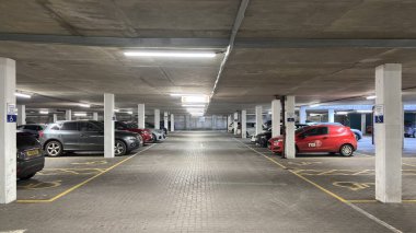 Karanlık yeraltı otoparkı. Şehirli grunge modern yaşam. Huysuz beton bina. Park etmiş arabalar. Sütunlar. Yol. Endüstriyel vahşi modernizm.