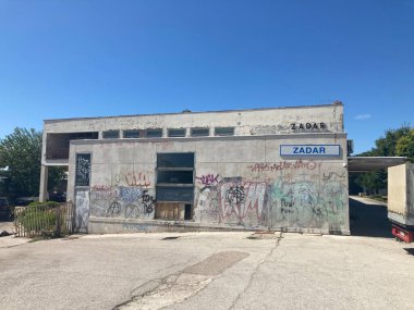 Hırvatistan 'ın Zadar kentindeki terk edilmiş tren istasyonu. Beton bina ve grafiti ile demiryolu rayları terk edilmiş ıssız harabe demiryolu taşımacılığı