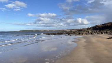 İskoçya 'da Edinburgh yakınlarındaki Aberlady Plajı. Açık bir bahar gününde rüzgârlı bir sahil. Hafif bulutlar, altın kum, silip süpüren sahil ve deniz kıyıları