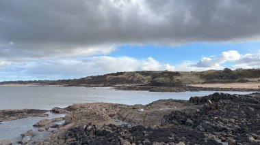 İskoçya 'da Edinburgh yakınlarındaki Aberlady Plajı. Açık bir bahar gününde rüzgârlı bir sahil. Hafif bulutlar, altın kum, silip süpüren sahil ve deniz kıyıları