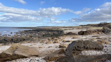İskoçya 'da Edinburgh yakınlarındaki Aberlady Plajı. Açık bir bahar gününde rüzgârlı bir sahil. Hafif bulutlar, altın kum, silip süpüren sahil ve deniz kıyıları
