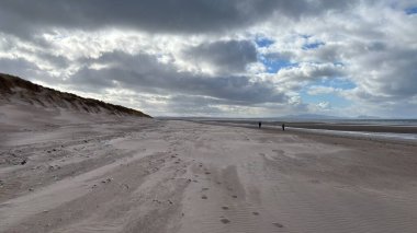 İskoçya 'da Edinburgh yakınlarındaki Aberlady Plajı. Açık bir bahar gününde rüzgârlı bir sahil. Hafif bulutlar, altın kum, silip süpüren sahil ve deniz kıyıları
